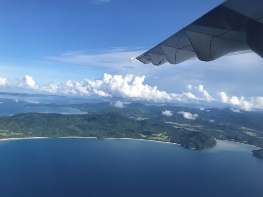 Aircraft flies along island beach