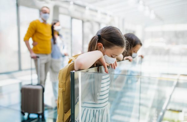 Family with two children going on holiday, wearing face masks at the airport.