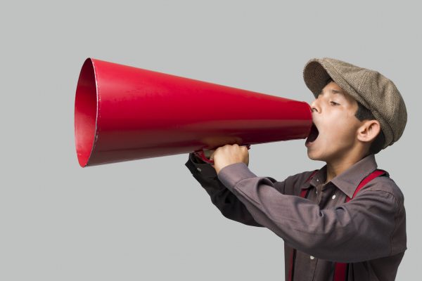 Little boy with newsboy cap shouting on old fashioned megaphone